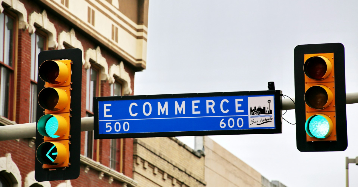 Street sign for E Commerce in San Antonio, flanked by traffic lights, one displaying a green arrow—much like the promising pathway to eCommerce success.