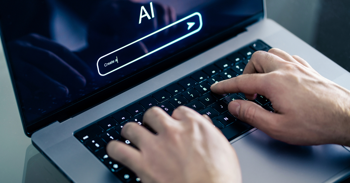 Hands typing on a laptop keyboard with a screen displaying "AI" and a search bar, highlighting the latest AI tools for marketers in 2024.