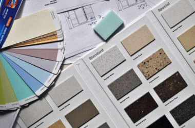 Assorted paint color swatches and countertop material samples displayed on top of architectural plans, perfect for those starting interior design or joining the interior design business.
