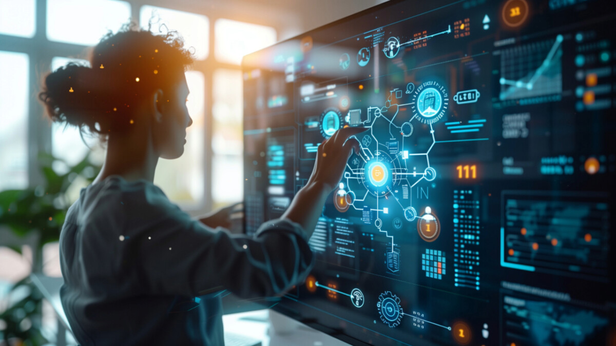 A person interacts with a large digital touchscreen displaying data charts, graphs, and artificial intelligence-driven interface elements in a modern office setting.