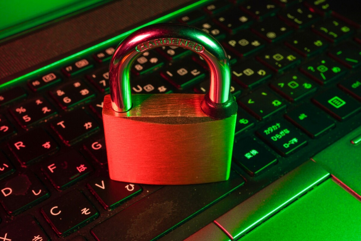 A brass padlock sits on a black computer keyboard with Japanese characters, illuminated by red and green lighting—symbolizing the importance of secure medical devices in today's digital landscape.