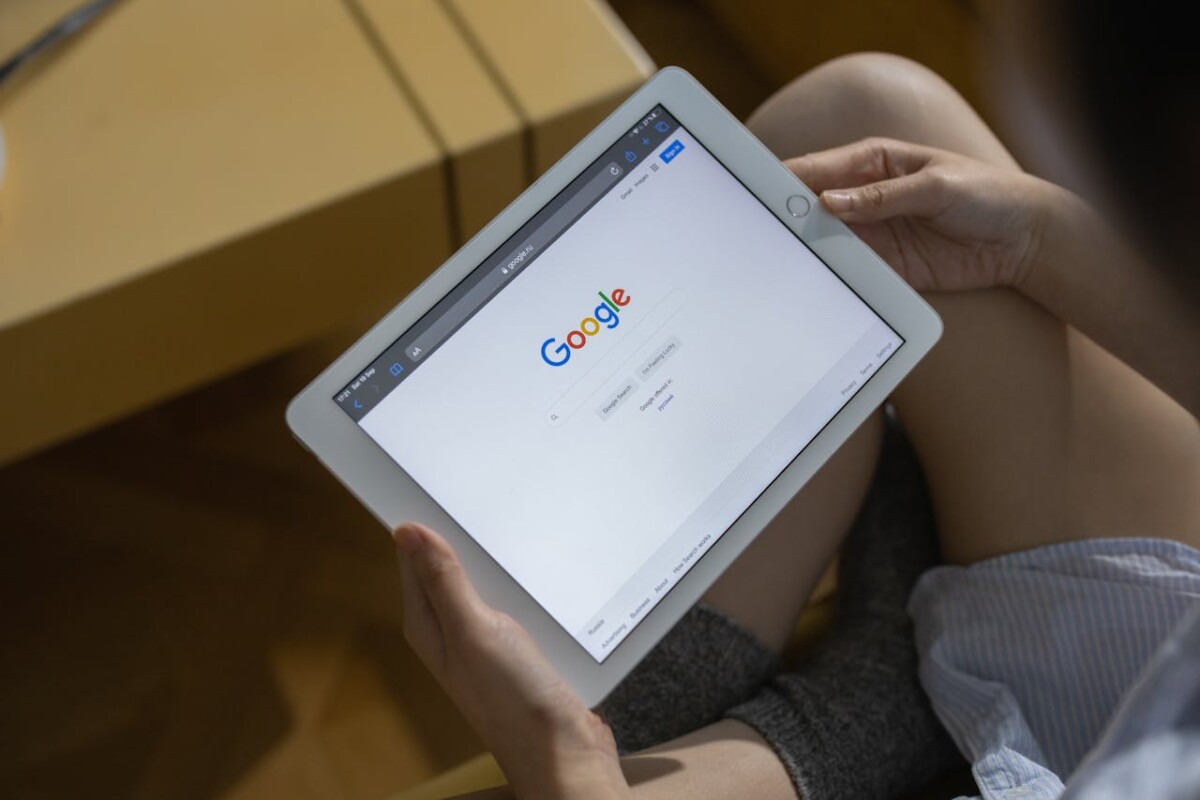 A person holding a tablet displaying the Google search homepage, highlighting the impact of Google's AI Overviews on SEO.