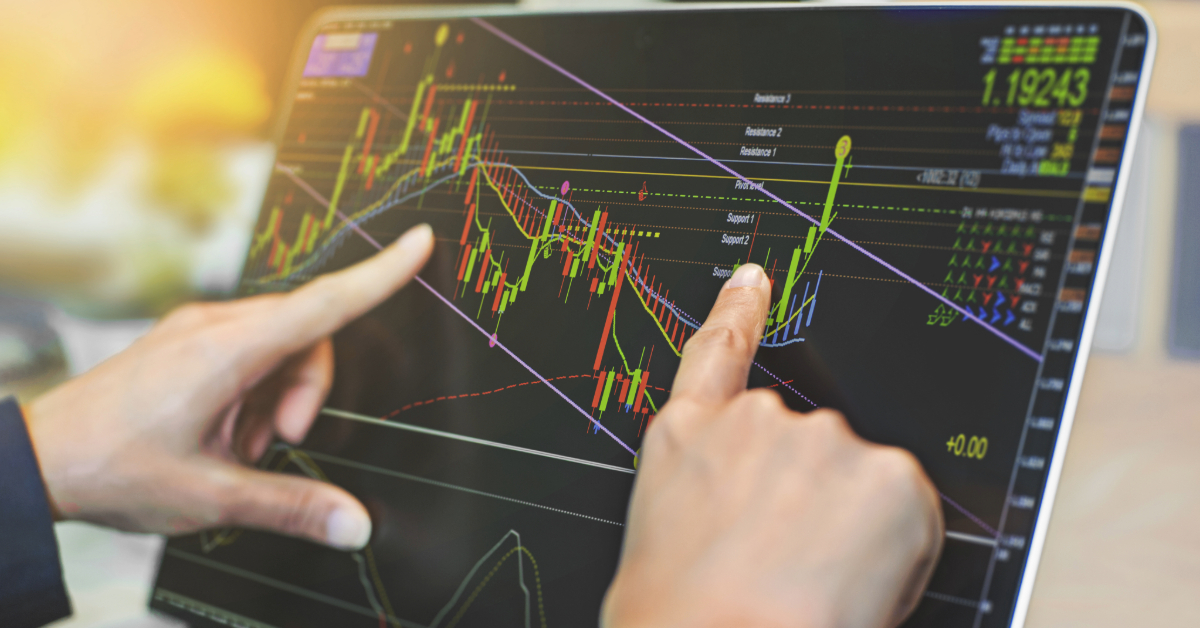 Hands point at a laptop screen displaying technical stock charts with colorful trend lines, candlesticks, and various indicators for financial market analysis, highlighting the key drivers behind DAX growth.