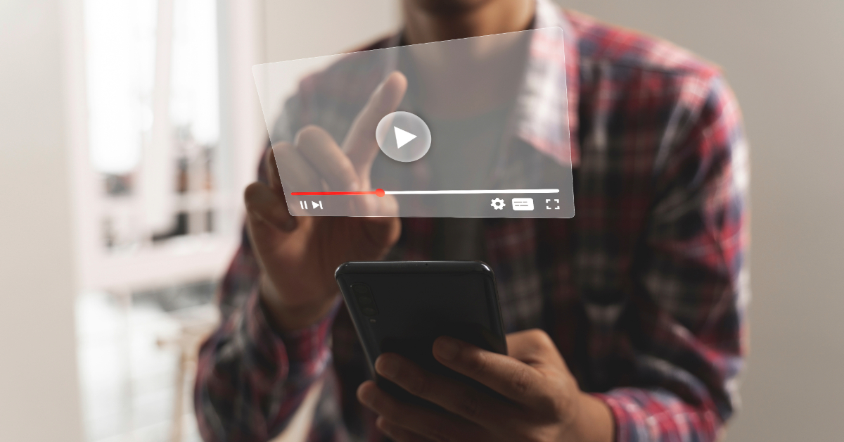 Person in a plaid shirt uses a smartphone while interacting with a floating transparent video player interface, exploring how to download online videos seamlessly.