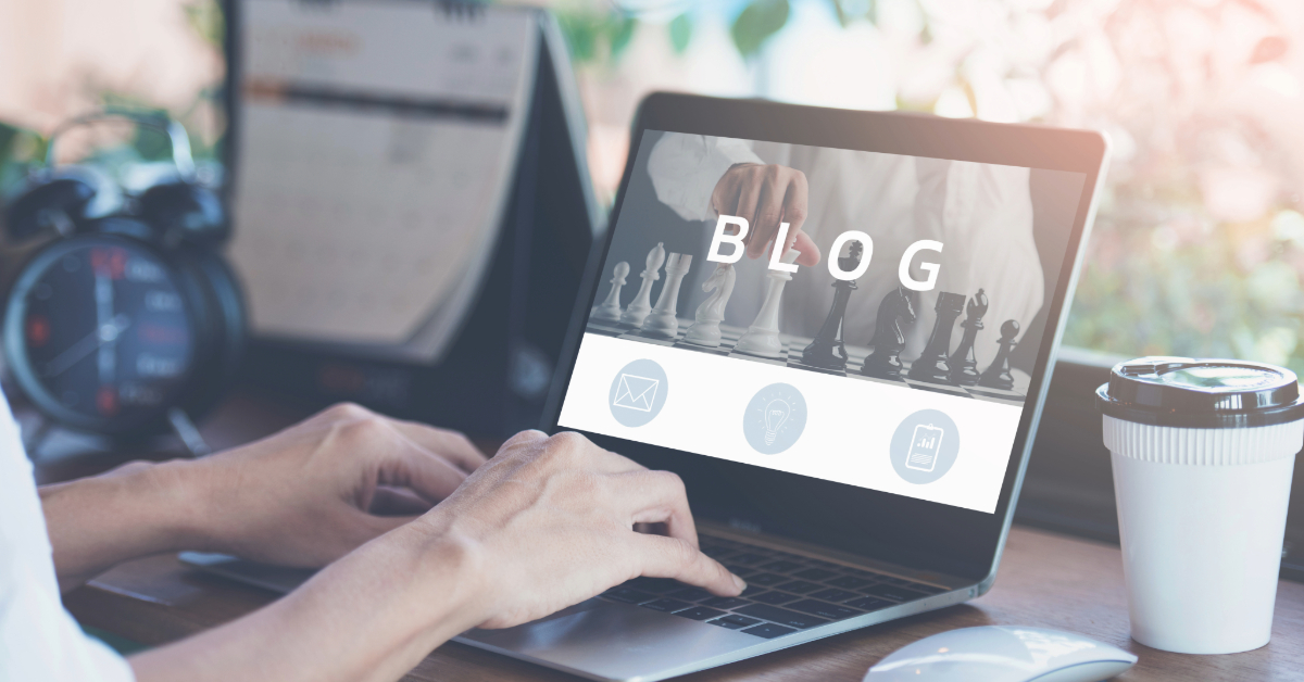 Person typing on a laptop displaying "BLOG" and icons, with a chessboard image in the background—highlighting expert blog content that supports brand building.