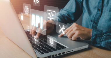 Person typing on a laptop with floating digital icons, including "API," coding symbols, a wrench, and a padlock, representing software development and Ecommerce APIs for modern programming solutions.