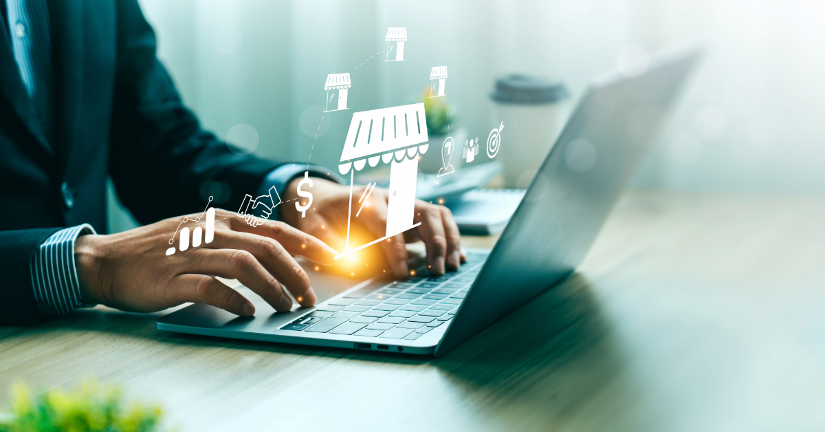 Person typing on a laptop with digital graphics of a storefront and financial icons, representing the obstacles of running a business or launching a trademarked business in e-commerce.