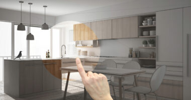 A hand points toward a modern kitchen, with part of the image rendered in full color and the rest in a sketch style, capturing the creative process of an interior design business. A bird stands on the kitchen island.