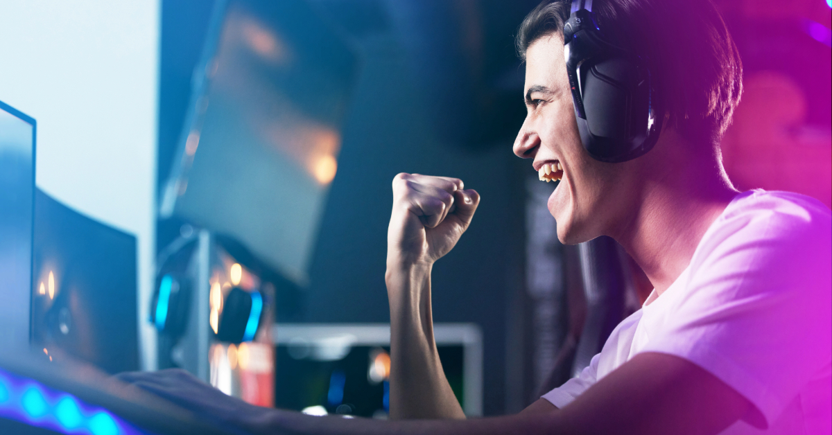A person wearing headphones sits at a computer, smiling broadly and raising a fist in excitement, likely while gaming—perhaps celebrating the benefits of enhanced gaming security or Skycheat integration.