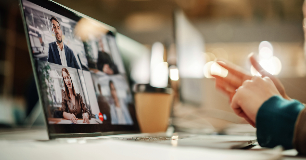 A person participates in a video conference on a laptop, displaying four people in a virtual meeting—an example of remote work powered by smart office solutions.