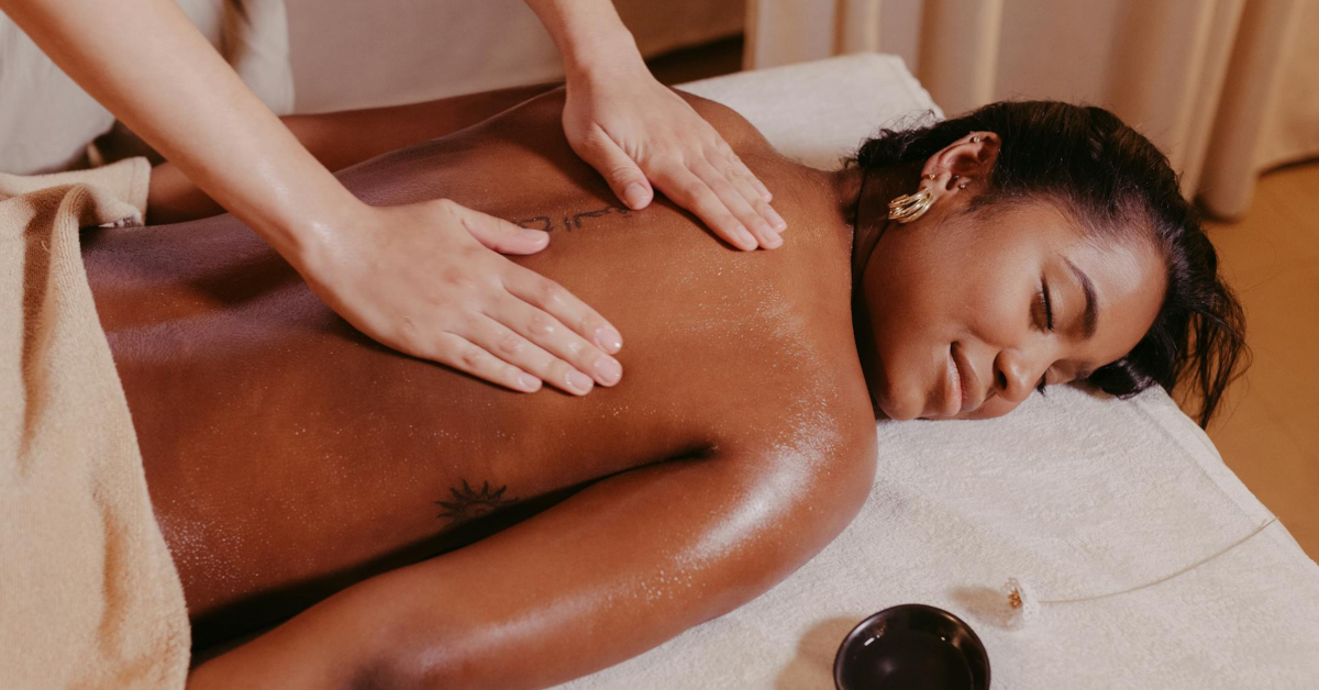A person lies face down on a massage table with eyes closed while receiving a back massage in a spa setting, highlighting the relaxing atmosphere essential for creating a massage business.