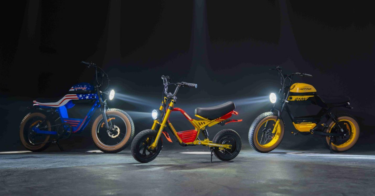 Three E-Bikes with headlights on are displayed in a dark room; the blue, red, and yellow bikes feature unique designs and tire sizes—highlighting a revolution in sustainable rides for a greener future.