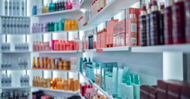 Shelves filled with various bottles and containers of hair and beauty products, organized by color and type in a well-lit store or salon—an inviting scene that reflects expert cosmetics marketing and maintaining demand in today’s eCommerce cosmetics landscape.