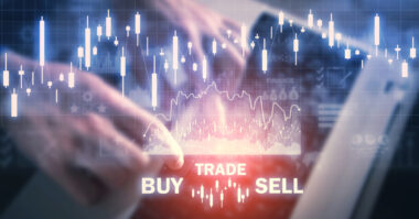 A person uses a tablet with digital graphs, candlestick charts, and the words "BUY," "TRADE," and "SELL" displayed, illustrating online financial trading during a Prop Trading Challenge.