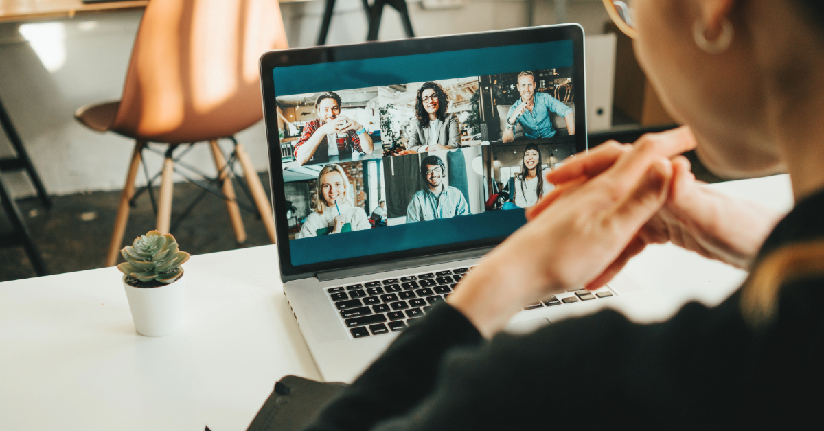Person sitting at a desk participating in a white label video conferencing session with six people displayed on a laptop screen, enhancing client interaction.