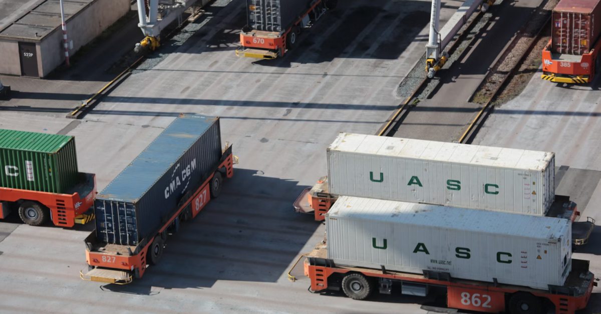 Aerial view of automated vehicles, part of the rise in the trucking industry, transporting shipping containers labeled CMA CGM and UASC at a port terminal.