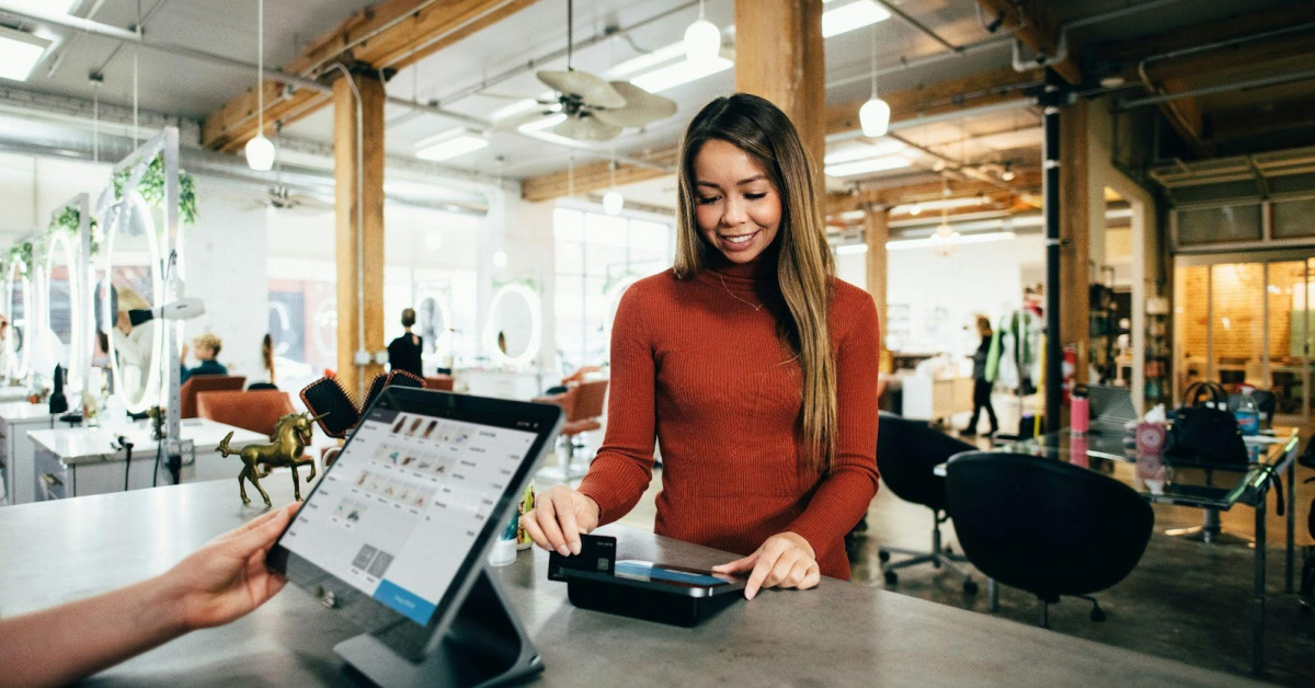 A woman uses a credit card to pay at a point-of-sale terminal in a modern, well-lit store, where AI in customer service enhances the shopping experience and fosters customer loyalty.