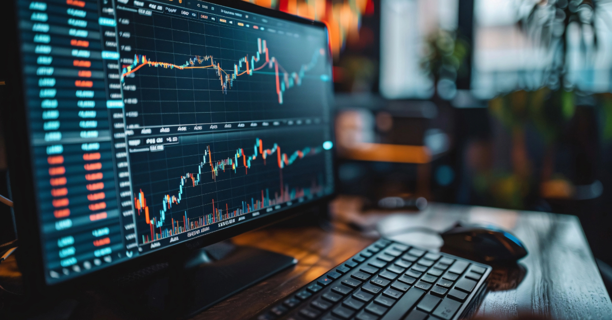 A computer monitor displays financial charts and stock market data, highlighting cryptorobotics tools and trade strategies, with a keyboard and mouse on the desk in a modern office setting.