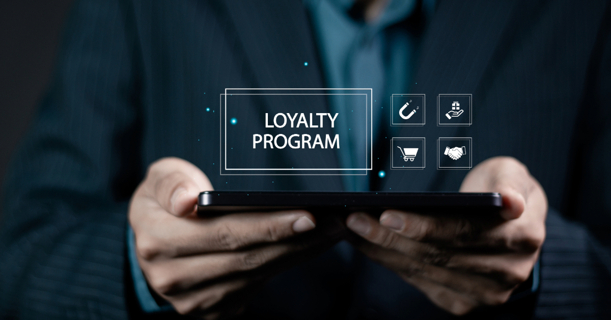A person in a suit holds a tablet displaying a digital overlay reading "Loyalty Program," with icons for rewards and shopping—perfect for a 2025 CFO guide to innovative loyalty programs.