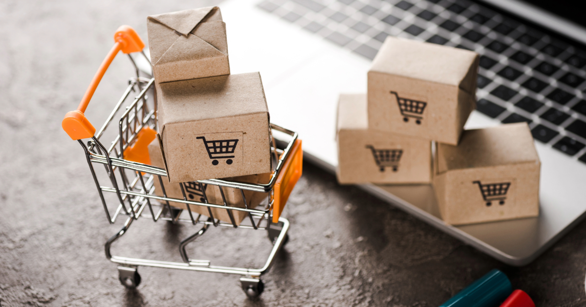 A miniature shopping cart with small cardboard boxes beside a laptop keyboard, highlighting online shopping, e-commerce tools, and enhanced customer engagement.